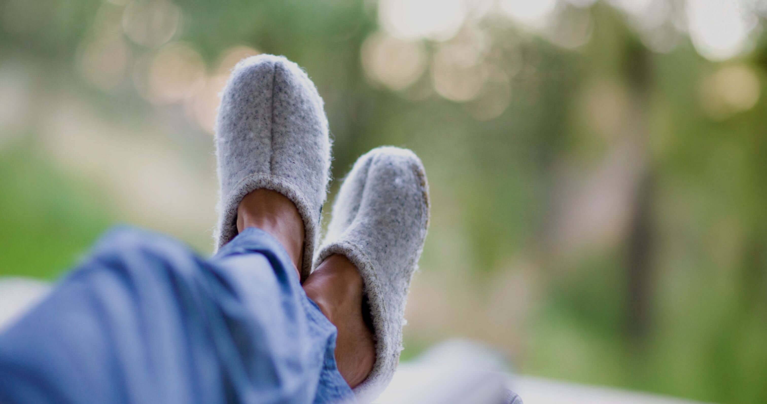 Man sitter ute på altanen med korsade ben, iklädd blå pyjamasbyxor och ljusgrå tofflor från Ulle